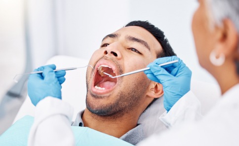 Patient receiving a dental checkup with professional tools in a modern clinic.